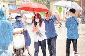 Thanh niên tình nguyện che ô, hỗ trợ thí sinh vào phòng thi.