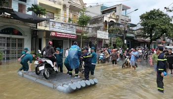 Lực lượng dân quân phường Minh Khai, thành phố Hà Giang đưa người dân qua đoạn đường ngập úng.