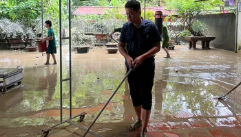 Hộ gia đình chủ động gạt bùn, làm vệ sinh nhà ở sau ngập nước.