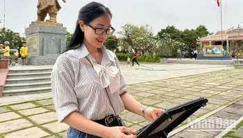 Cô giáo Trần Thị Bích Phương check-in bảng gắn chip NFC thuộc Dự án "Yêu lắm Việt Nam" của Báo Nhân Dân tại Di tích Đền thờ Nguyễn Hữu Cảnh.