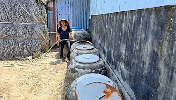 Bà Lý Thị Xuyên bơm nước dưới ao chứa vào lu, xử lý lại bằng phèn chua để có nước tắm, giặt.