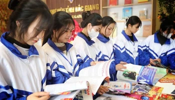 Các em học sinh đọc sách tại gian trưng bày chào mừng 50 năm Ngày Giải phóng miền nam, thống nhất đất nước tại Thư viện Bắc Giang.