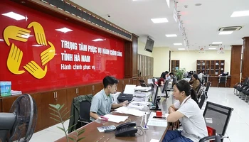 Cán bộ, công chức Trung tâm hành chính công tỉnh Hà Nam giải quyết thủ tục hành chính cho người dân. (Ảnh ĐÀO PHƯƠNG)