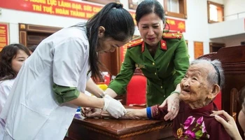 Cán bộ, chiến sĩ Công an và nhân viên Công ty GeneStory tiến hành thu nhận mẫu ADN mẹ liệt sĩ. (Ảnh: Công an tỉnh Đắk Lắk)