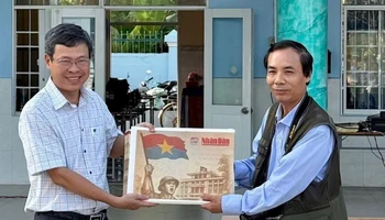 Nhà báo Trọng Duy, đại diện Văn phòng Báo Nhân Dân tại Bạc Liêu trao Phụ san đặc biệt của Báo Nhân Dân đến thầy giáo Dương Bình, Bí thư Chi bộ, Hiệu trưởng Trường Trung học phổ thông Chuyên Bạc Liêu.