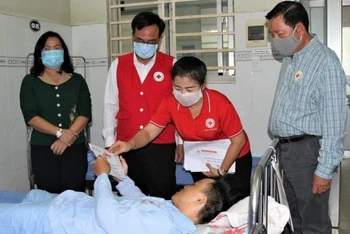 Đại diện Hội Chữ thập đỏ tỉnh Đồng Nai trao tiền hỗ trợ cho nạn nhân bị thương, đang điều trị tại bệnh viện.