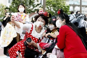 Du khách tới Công viên giải trí Disneyland Tokyo phải đeo khẩu trang bắt buộc (Ảnh: CNN)