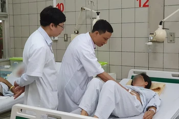 TS, BS Trần Mạnh Hùng và BS Trần Quế Sơn thăm khám cho bệnh nhân trước khi xuất viện.