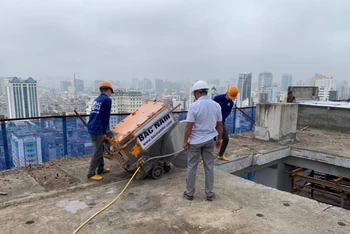 Công nhân Công ty Đầu tư xây dựng Bắc Nam tiến hành cắt sàn bê-tông mái tầng 18 công trình sai phạm số 8B phố Lê Trực.