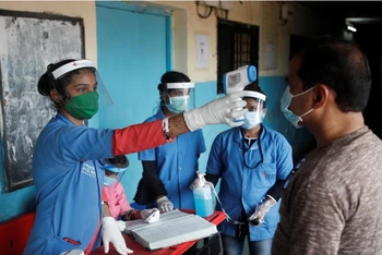 Nhân viên y tế đo thân nhiệt cho người dân tại một trường học ở Mumbai, Ấn Độ, ngày 10-8. (Ảnh: Reuters)