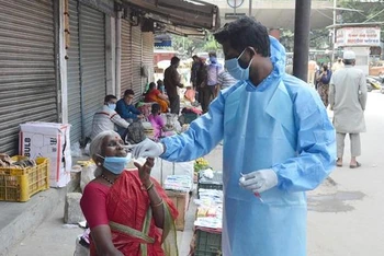 Nhân viên y tế lấy mẫu dịch xét nghiệm Covid-19 cho người dân tại một khu chợ ở Bangalore, Ấn Độ ngày 30-8-2020. (Ảnh: THX/TTXVN)