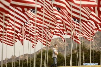 Một người phụ nữ đi dưới những lá cờ tại Trường đại học Pepperdine, thành phố Malibu, bang California, Mỹ, ngày 11-9-2020. (Ảnh: Xinhua)