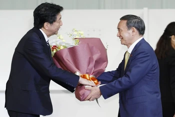 Ông Yoshihide Suga tặng hoa cho ông Shinzo Abe sau khi ông được bầu làm Chủ tịch LDP thay ông Abe, ngày 14-9. (Ảnh: Kyodo)