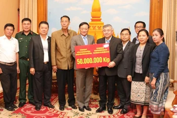 Đại sứ Việt Nam tại Lào Nguyễn Bá Hùng (thứ 5 từ trái qua) trao số tiền ủng hộ Lào, chiều 26-10.