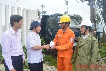 Chủ tịch UBND tỉnh Quảng Ngãi Đặng Văn Minh (thứ hai từ trái sang) động viên công nhân ngành điện vượt qua khó khăn trong việc khôi phục lưới điện bị hư hỏng. (Ảnh: HIỂN CỪ)