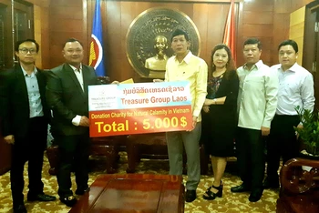 Tổng Lãnh sự Nguyễn Đăng Hùng (phải) đón nhận số tiền ủng hộ của ông Sisombat Douangvilaykeo (trái), chiều 31-10.