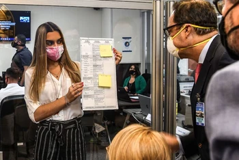Các nhân viên bầu cử kiểm tra một lá phiếu được bầu qua đường bưu điện tại Miami, ngày 3-11-2020. (Ảnh: Getty Images)
