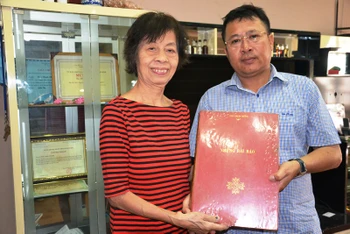 Bà Phan Thu Hương trao tài liệu của nhà báo Trần Thanh Phương cho đồng chí Lê Nam Tư - Trưởng Cơ quan thường trực Báo Nhân Dân tại TP Hồ Chí Minh.