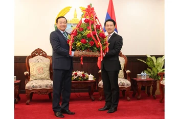 Đại sứ Việt Nam tại Lào Nguyễn Bá Hùng (trái) và Bộ trưởng Ngoại giao Lào Saleumxay Kommasith bên lẵng hoa tươi thắm chúc Quốc khánh Lào lần thứ 45. 