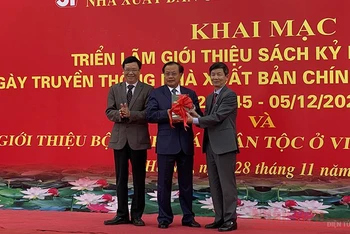 Đồng chí Phạm Quang Nghị, nguyên Ủy viên Bộ Chính trị, nguyên Bí thư Thành ủy Hà Nội nhận bộ sách từ lãnh đạo NXB và đại diện nhóm tác giả. Ảnh: TRỊNH DŨNG
