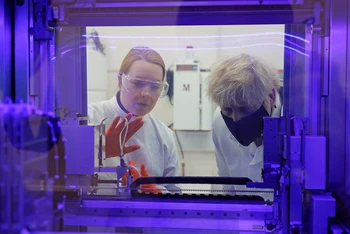 Thủ tướng Anh Boris Johnson (bên phải) đang quan sát máy xét nghiệm PCR (xét nghiệm virus SARS-CoV-2) cùng với nhà khoa học y sinh. Ảnh: AP.