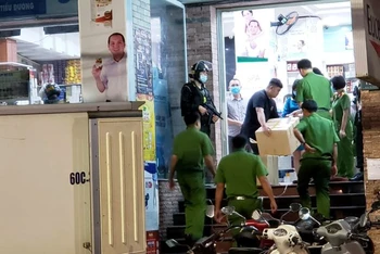 Lực lượng công an đưa nhiều thùng  carton bên trong chứa thuốc không rõ nguồn gốc ra xe chuyên dụng ở Công ty TNHH dược phẩm Sơn Minh, số 135, đường Phan Đình Phùng.