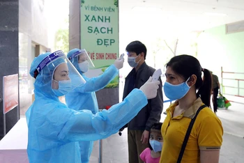 Kiểm tra thân nhiệt cho người bệnh đến khám, chữa bệnh tại Bệnh viện Xanh-Pôn (Hà Nội). Ảnh: ĐĂNG ANH