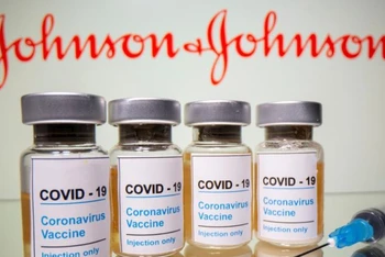 Lọ vaccine ngừa Covid-19 được chụp trước biểu trưng của Johnson & Johnson. Ảnh: Reuters.