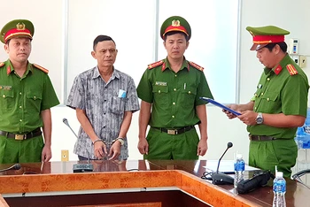 Cơ quan Cảnh sát điều tra Công an tỉnh Bình Thuận đọc Quyết định khởi tố bị can, Lệnh bắt tạm giam đối với Trần Văn Đông (áo sơ mi) tại nơi làm việc.