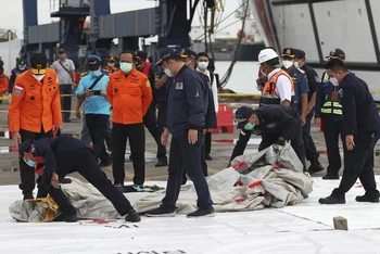 Lực lượng cứu hộ kiểm tra các mảnh vỡ được tìm thấy dưới nước ngoài khơi đảo Java. (Ảnh: AP)