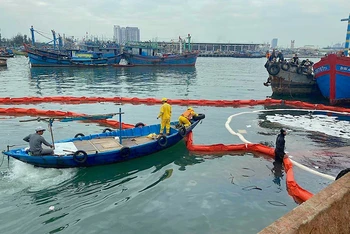 Lực lượng chức năng xử lý vết dầu tràn tại Âu thuyền và Cảng cá Thọ Quang.