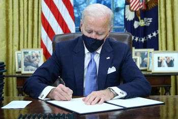Tổng thống Mỹ Joe Biden ký các sắc lệnh tại phòng Bầu Dục của Nhà Trắng, ở Washington, Mỹ, sau khi ông tuyên thệ nhậm chức ngày 20-1-2021. (Ảnh: Reuters)