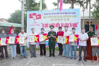 Đại tá Lê Văn Anh, Phó chính uỷ, BĐBP tỉnh trao cờ tổ quốc và ảnh Bác Hồ cho ngư dân.