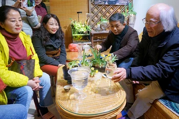Nghệ nhân Nguyễn Phú Cường (ngoài cùng bên phải) hướng dẫn cách chăm sóc hoa thủy tiên.