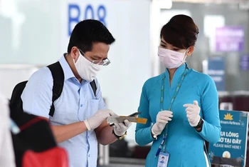 Nhân viên phục vụ mặt đất của VNA hướng dẫn hành khách khai báo y tế trước chuyến bay. (Ảnh: VNA)