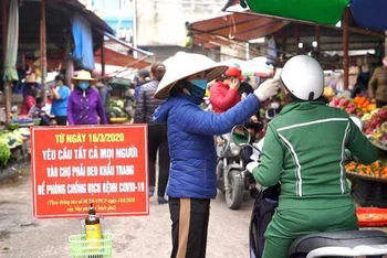 Kiểm tra thân nhiệt cho người dân tại chợ trung tâm TP Cẩm Phả (Quảng Ninh).