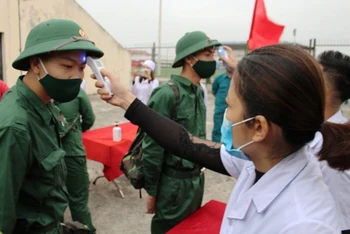 Nhân viên y tế huyện Quảng Xương kiểm tra thân nhiệt các tân binh trước lễ giao, nhận quân năm 2021.