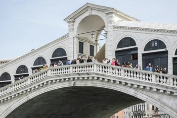 Du khách tới thăm cây cầu Rialto ở Venice, miền bắc Italy hôm 1-5. Italy đang dần mở cửa trở lại sau sáu tháng đóng cửa để ngăn chặn Covid-19. (Ảnh: AP)