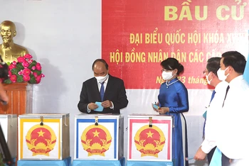 Chủ tịch nước Nguyễn Xuân Phúc cùng phu nhân bỏ phiếu tại khu vực bỏ phiếu số 041, đơn vị bầu cử số 9, thị trấn Củ Chi, huyện Củ Chi, TP Hồ Chí Minh.