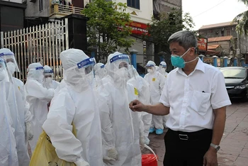 Thứ trưởng Nguyễn Trường Sơn trao đổi, động viên cán bộ y tế thực hiện lấy mẫu ngoài cộng đồng. 