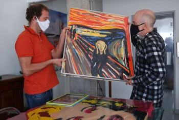 Nghệ sĩ Brazil Eduardo Srur và trợ lý Rogerio Canella đã tái hiện bức tranh “Tiếng thét” của Edvard Munch từ rác nhựa trong loạt triển lãm “Thiên nhiên nhựa” tại phòng tranh của ông ở Sao Paulo, Brazil ngày 27-5. Ảnh: Reuters.