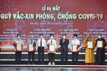Thủ tướng Phạm Minh Chính và các đồng chí lãnh đạo trao chứng nhận và tặng hoa cho các tập thể, cá nhân đã đóng góp ủng hộ Quỹ Vaccine phòng, chống Covid-19, tối 5-6. (Ảnh: TRẦN HẢI)