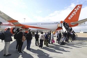 Hành khách chuẩn bị lên máy bay khởi hành từ sân bay Gatwick, Anh, tới Bồ Đào Nha, ngày 17-5. (Ảnh: AP)