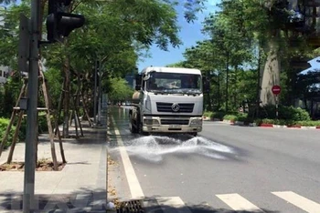 Công ty TNHH MTV Môi trường Đô thị Hà Nội, Chi nhánh Đống Đa thực hiện tưới nước làm mát, giảm bụi tại tuyến đường Hoàng Cầu (Đống Đa) trong những ngày nắng nóng. (Ảnh: TTXVN)