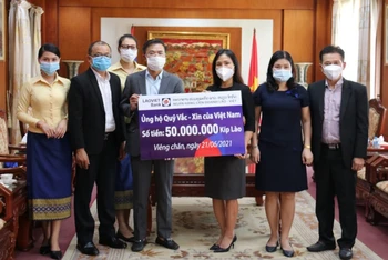 Tổng Giám đốc LaoVietBank Nguyễn Đức Vũ (trái) trao 50 triệu kíp Lào đóng góp vào Quỹ Vaccine phòng Covid-19, chiều 21-6.