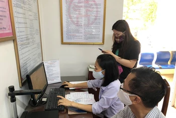 Cán bộ bộ phận một cửa phường Ngọc Lâm (quận Long Biên, Hà Nội) hướng dẫn công dân và nhập trên máy tính thực hiện dịch vụ công mức độ 3.