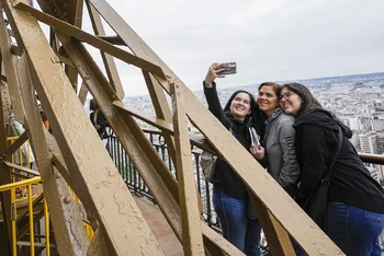 Du khách hào hứng chụp ảnh với toàn ảnh thành phố Paris từ Tháp Eiffel (Ảnh: AP)