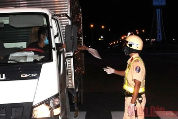 Lực lượng Cảnh sát giao thông Công an thành phố Hồ Chí Minh kiểm tra một lái xe tải tại Trạm kiểm dịch đặt trên đường Điện Biên Phủ, quận 1 vào tối ngày 26/7. 