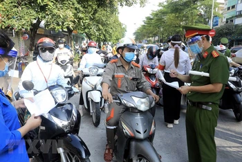 Lực lượng chức năng kiểm tra giấy tờ tùy thân và xác nhận đi làm, ra ngoài của cơ quan với người dân lưu thông trên đường Đào Tấn, Hà Nội, sáng 28/7.