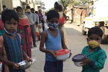 Trẻ em xếp hàng nhận gạo và đậu cứu trợ tại một khu ổ chuột ở khu Kapasheda, Delhi, ngày 7/4. Ảnh: Al Jazeera.